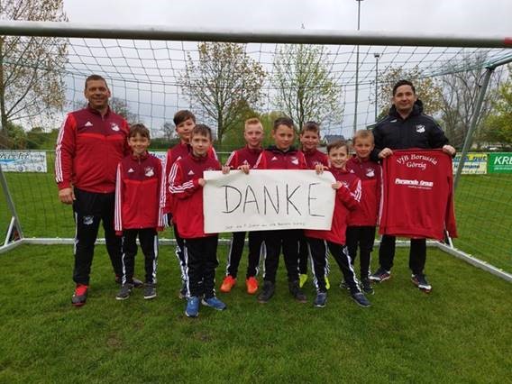 Gruppenfoto der F-Jugend des VfB Borussia Görzig e.V. mit ihren neuen Trainingsanzügen halten ein DANKE-Plakat.